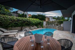 聖拉斐爾的住宿－Rez de villa de charme-piscine-3 chambres 6 pers，一张带椅子的木桌和一把遮阳伞,毗邻游泳池