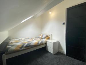 a bedroom with a bed and a white wall at Pristine 2 bedroom apartment with off street parking in Norwich