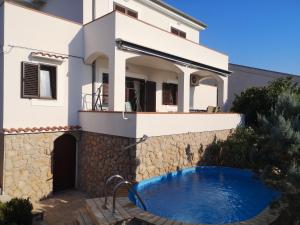 a villa with a swimming pool in front of a house at Willa Ferry **** in Prizna
