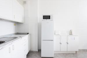 a white kitchen with white cabinets and a refrigerator at Home2Book Sea Front Vista Marina, Los Cristianos in Arona
