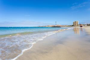 a beach with the ocean and people walking on it at Home2Book Sea Front Vista Marina, Los Cristianos in Arona