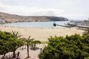 a beach with people in the water and a pier at Home2Book Sea Front Vista Marina, Los Cristianos in Arona