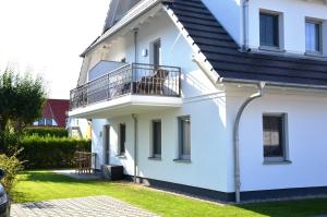 a white house with a balcony and grass at Whg 03 - Keekwind in Zingst