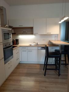 eine Küche mit weißen Schränken sowie einem Tisch und Stühlen in der Unterkunft Ferienwohnung Christa in Graz