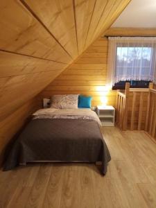 a bedroom with a bed in a wooden room at Siedlisko Czarny Dzięcioł in Narewka