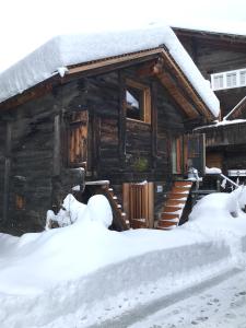 Cabaña de madera con nieve en el techo en Ferienhaus Z‘ Gädi, en Ernen