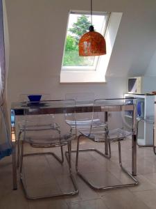 a glass table with two clear chairs and a lamp at FeWo Gottorf in Ulsnis