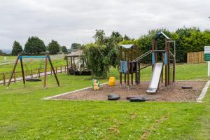 a park with a playground with a swing set at The Pine Lodge in Aberystwyth