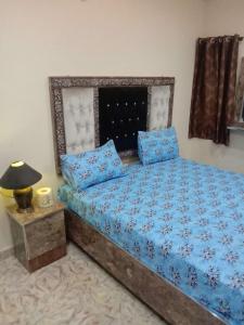 a bedroom with a bed with blue sheets and a lamp at NTP Hotel in Lahore