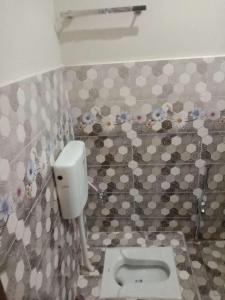a bathroom with a toilet in a tiled wall at NTP Hotel in Lahore
