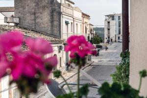 a view of a street with pink flowers in a window at Aurà - Guest House Iblea in Ragusa