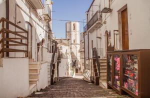 an alley in an old town with a tower at Rooms Gli Arcangeli - Affitti Brevi Italia in Monte SantʼAngelo