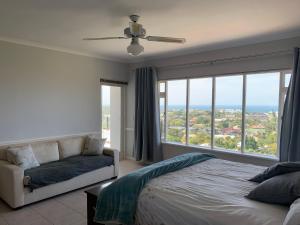 a bedroom with a bed and a couch and large windows at 56 Robberg Road Plettenberg Bay in Plettenberg Bay +30 photos