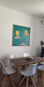 Casa da Carqueja 1 في كويمبرا: طاولة طعام مع كراسي و لوحة على الحائط