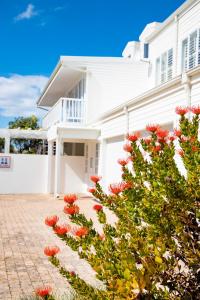 a white house with red flowers in front of it at Beach House 11A in Groot Brak Rivier