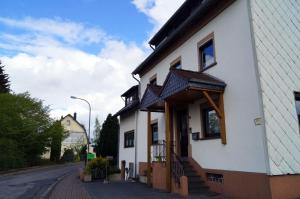 uma casa branca com um alpendre e escadas numa rua em Eifelferienhaus Thome em Lissendorf
