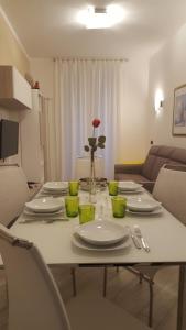 une table avec des assiettes et un vase avec une rose sur la table dans l'établissement Karina House-check in H 24, à Côme