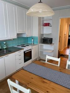 a kitchen with white cabinets and a table with chairs at Apartment Puistokatu in Kokkola +4 photos