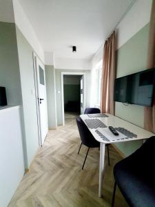a room with a desk and a table with chairs at Apartamenty Loft Rooms - centrum, bezpłatny parking in Ełk