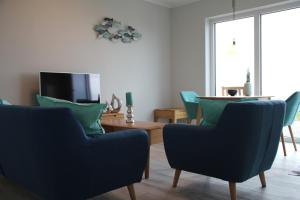 een woonkamer met blauwe stoelen en een tafel bij Meerblick Fehmarnsund 2 - direkt am Strand in Fehmarnsund