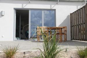 een houten tafel en stoel op een patio bij Meerblick Fehmarnsund 2 - direkt am Strand in Fehmarnsund