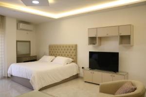 Schlafzimmer mit einem Bett und einem Flachbild-TV in der Unterkunft Amazing one Bedroom Apartment in Amman Elwebdah 7 in Amman