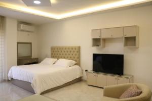 a bedroom with a bed and a flat screen tv at Amazing one Bedroom Apartment in Amman Elwebdah 5 in Amman