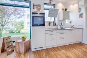 a kitchen with white cabinets and a large window at Strandburg Azurblau in Burgtiefe auf Fehmarn 