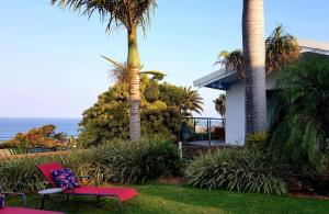 una casa con dos palmeras y una silla roja en ThE LaZy ShArK, en Freeland Park