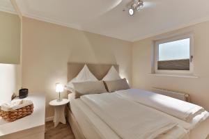 ein weißes Schlafzimmer mit einem großen Bett und einem Fenster in der Unterkunft Pebbles in Westerland