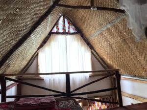 una finestra in una camera con tetto di paglia e tenda di Kalitusi Nature Resort a Fort Portal