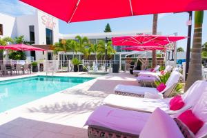 a pool with lounge chairs and umbrellas next to a hotel at The Saint Hotel in St Pete Beach