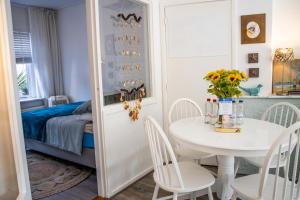 a white dining room with a table and a bed at Hippocampus aan Zee in Katwijk aan Zee