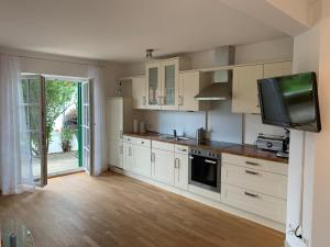 a kitchen with white cabinets and a flat screen tv at Golfsuite Axel in Uttlau-Haarbach in Haarbach