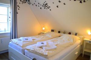 ein Schlafzimmer mit einem weißen Bett mit schwarzen Fledermäusen an der Wand in der Unterkunft Üüs letj Hüs in Wrixum
