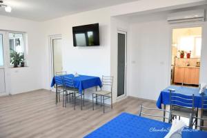 a dining room with blue tables and chairs and a television at Pensiunea La Codru in Jurilovca