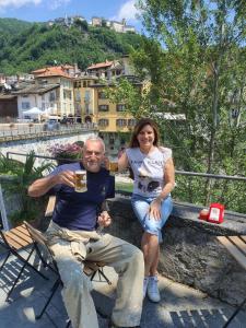 mężczyzna i kobieta siedzący na ławce ze szklanką piwa w obiekcie TIFFANY APPARTAMENTO w mieście Varallo