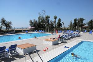 a pool with chairs and people in the water at Punta Falconera camping & village in Caorle