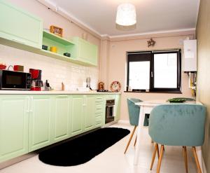 a kitchen with green cabinets and a table and chairs at La Stejari Apartment in Suceava