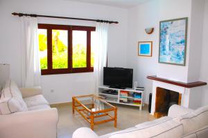 a living room with a fireplace and a tv at Villa Celia in Son Bou