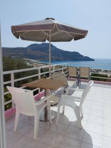 a table and chairs with an umbrella on a balcony at Camelia in Plakias