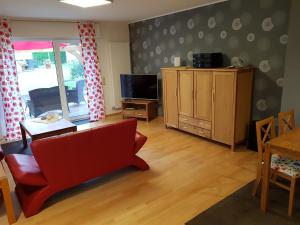 een woonkamer met een rode bank en een televisie bij Ferienwohnung Mohnblume in Rosdorf