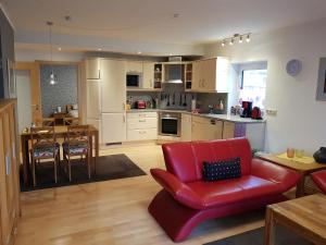a living room with a red chair and a kitchen at Ferienwohnung Mohnblume in Rosdorf