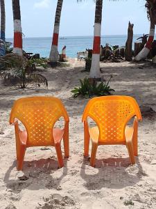 duas cadeiras laranja sentadas na praia em Sunny Beach Apartments em San Andrés