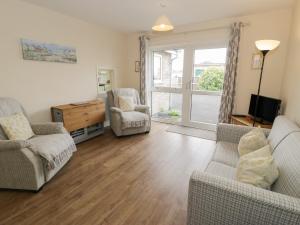 a living room with two chairs and a tv and a couch at 8 Dysynni Walk in Tywyn