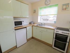 a small kitchen with white appliances and a window at 8 Dysynni Walk in Tywyn