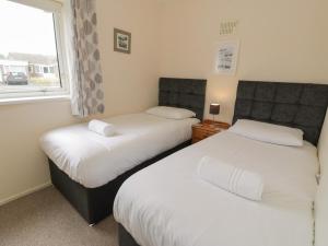two beds in a room with a window at 8 Dysynni Walk in Tywyn
