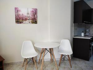 een keuken met een tafel en drie witte stoelen bij Anastasia's & Despoina's Apartment in Serres