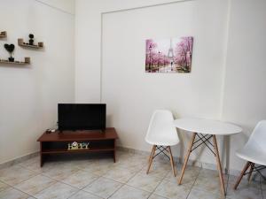 een woonkamer met een tv en een tafel en stoelen bij Anastasia's & Despoina's Apartment in Serres