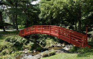 eine rote Brücke über einen Bach in einem Garten in der Unterkunft Fox & Bear Lodge in Glenwood